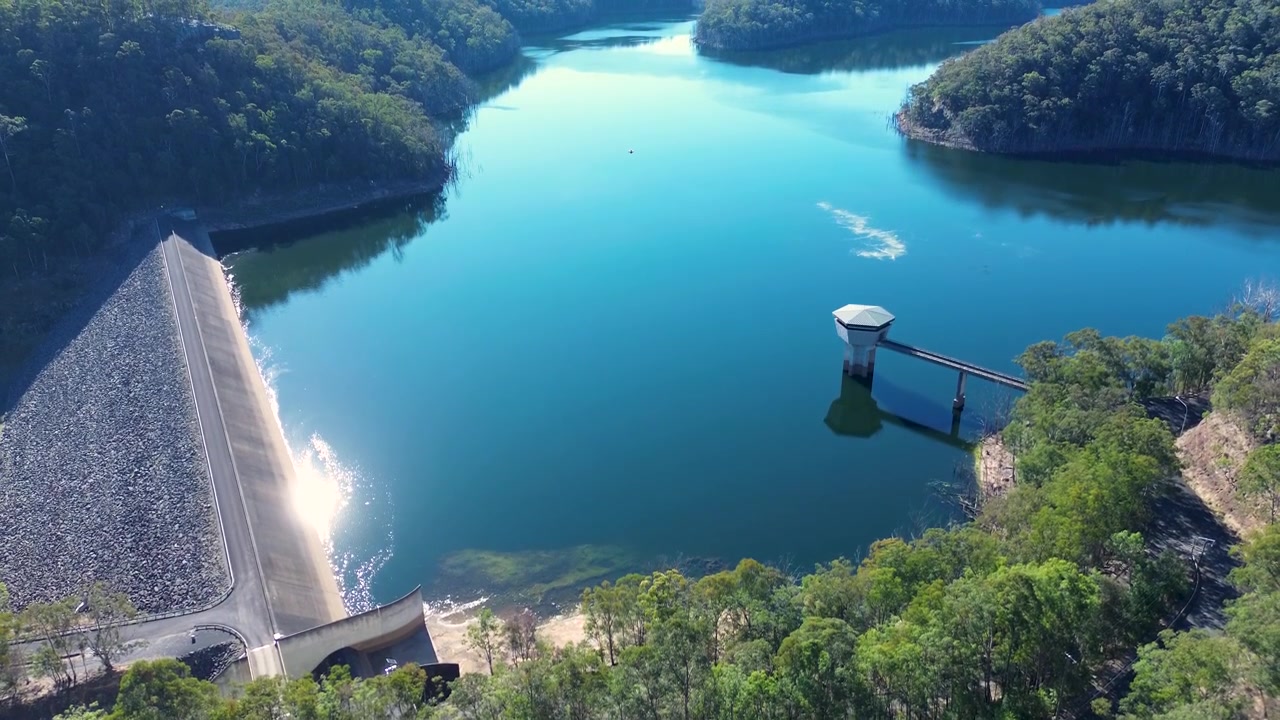Ilmakuva Mangrove Mountain Creekin padon tekojärvestä, jossa on vedenottotorni ja betoniseiniä, ympäröitynä Australian pensaikkometsällä lähellä Kulnuran infrastruktuuria Central Coastilla