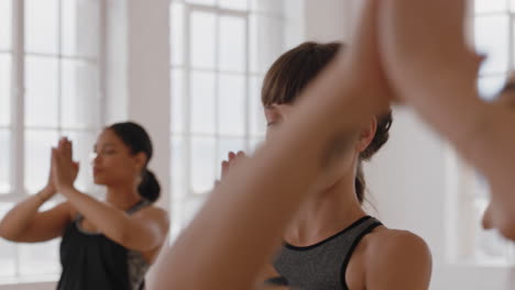 Mujer-De-Yoga-Caucásica-Saludable-Practicando-Meditación-En-Pose-De-Oración-Con-Un-Grupo-De-Mujeres-Multirraciales-Disfrutando-De-Un-Estilo-De-Vida-Físico-Ejercitando-Un-Cuerpo-Flexible-En-Un-Estudio-De-Entrenamiento.