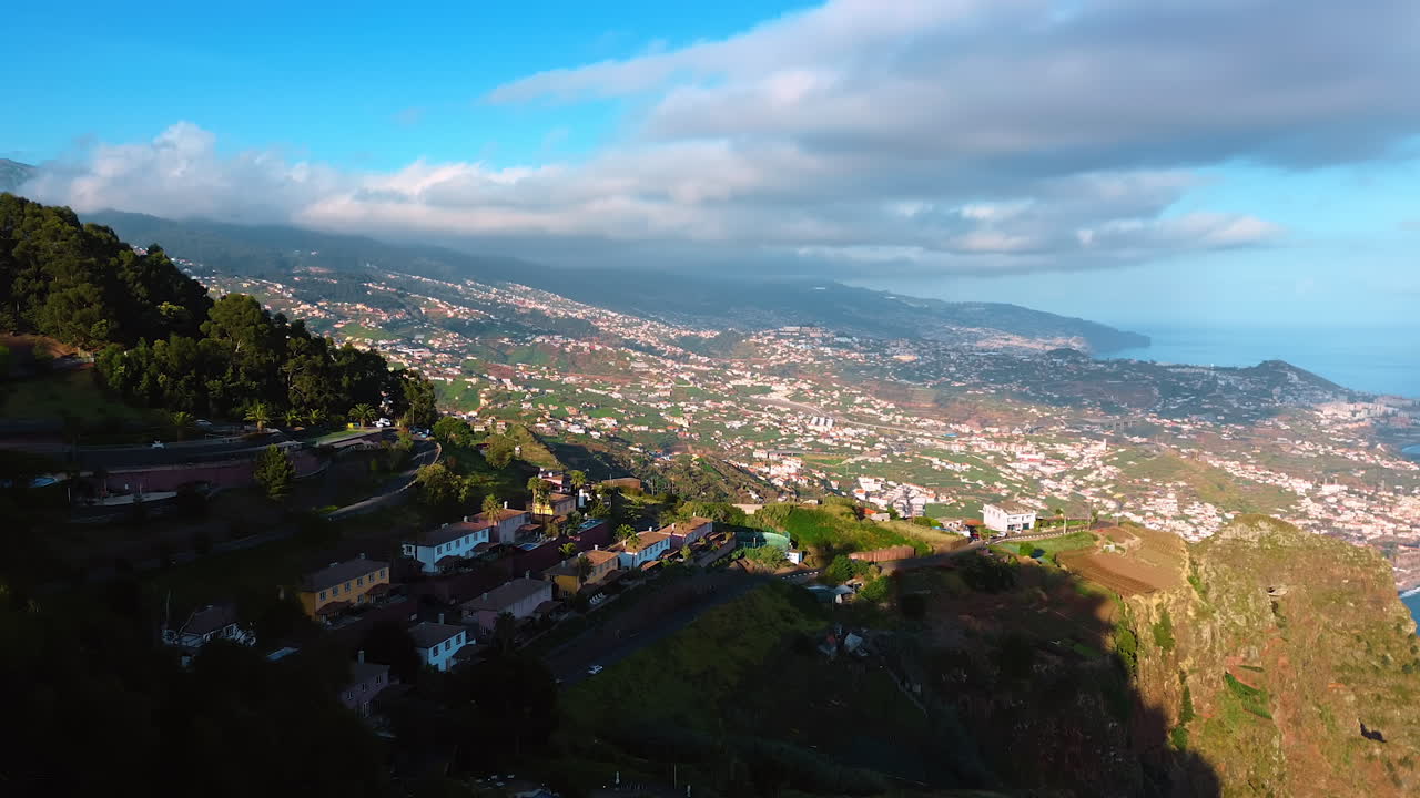 Tourists stand on the observation deck at the picturesque high mountain. Drone footage revealing view on the town located on the rocky slope. Madeira Islands, Portugal top view.
