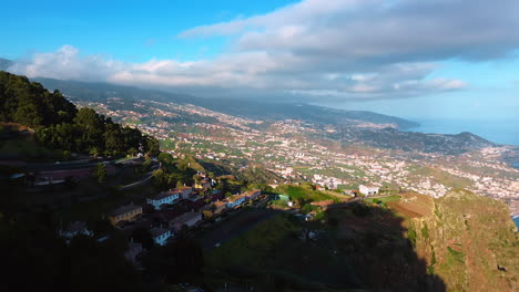 tourists stand on the observation deck at the picturesque high mountain. drone footage revealing view on the town located on the rocky slope. madeira islands, portugal top view.
