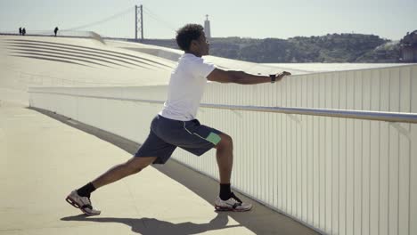 confident african american sportsman stretching legs before workout.