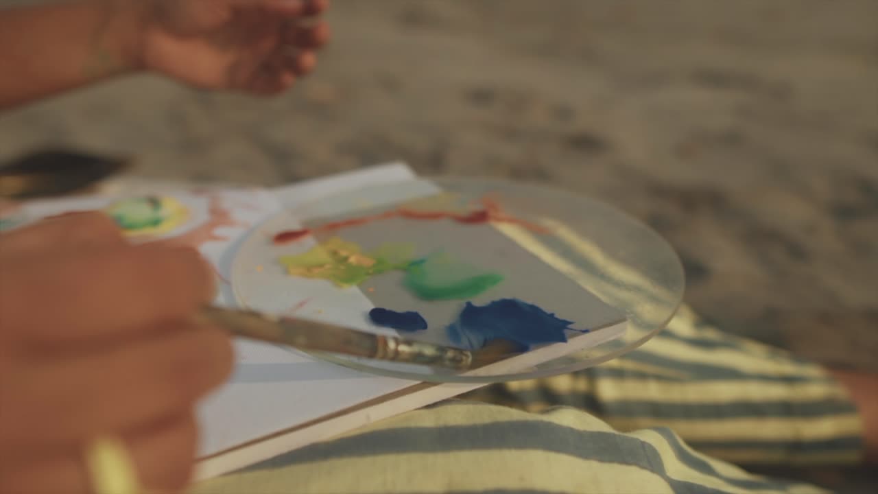 A young artist captures the beauty of a sunrise on a beach during low tide, meticulously working on her painting with background blurred