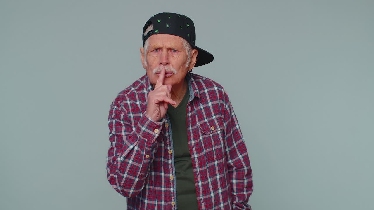 el hombre mayor presiona el dedo índice a los labios hace silencio gesto señal no dice secreto, shh estar callado