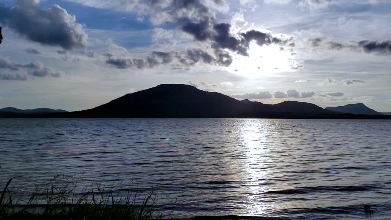 Lindo pôr do sol em time-lapse em movimento com água, nuvens, montanhas e céu