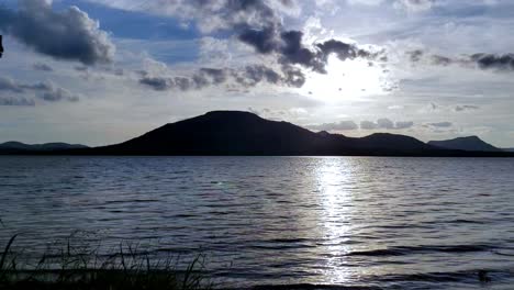 Wunderschöner-Bewegender-Zeitraffer-Sonnenuntergang-Mit-Wasser,-Wolken,-Bergen-Und-Himmel