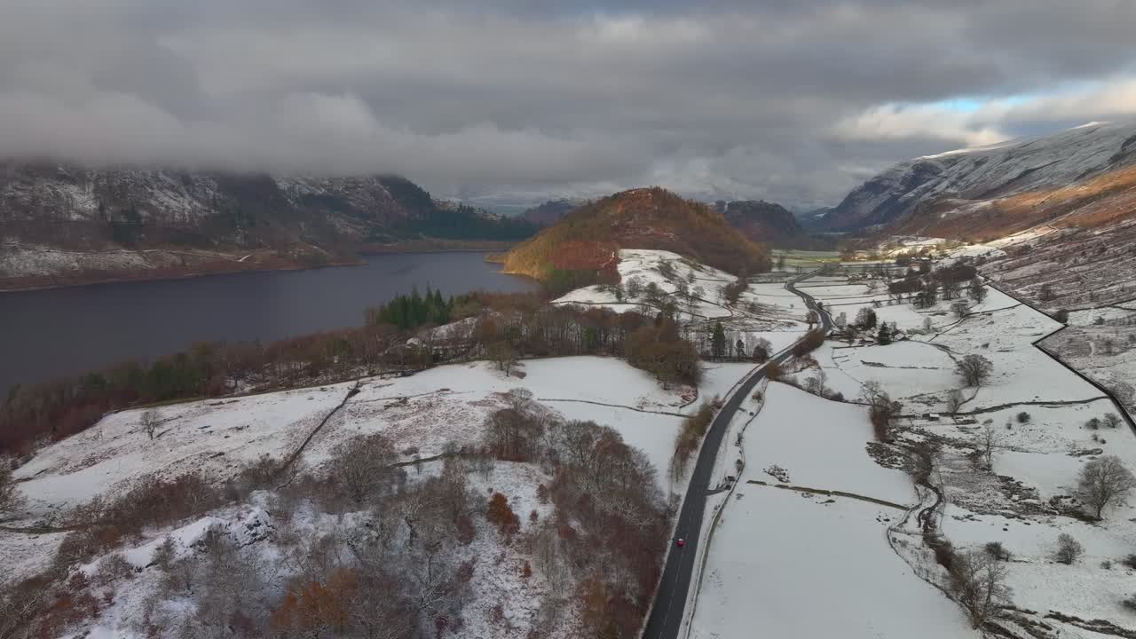 매우 가운 교통과 가운 눈 인 산과 겨울에 낮은 구름 개를 가진 어두운 호수와 도로, 브리아, 영국