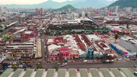 Flyover-of-old-houses-with-street-commerce-and-the-market-of-La-Vega-Central-in-Santiago-Chile,-poverty-and-disorder-all-around