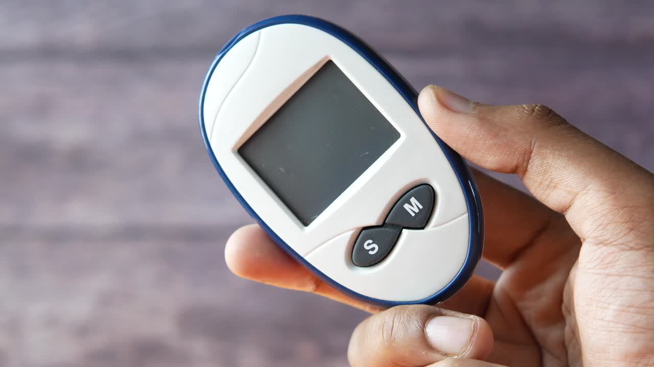 Hand holding a blood glucose meter