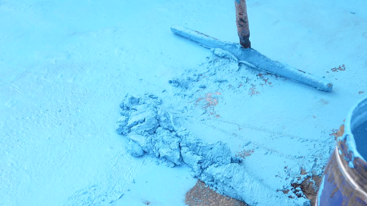 un piso azul está siendo pintado con un rodillo.