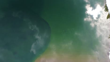 arriba directamente hacia abajo por encima de la nieve lago de agua verde forma de círculo reflejo nubes luz solar vívido fondo de agua de colores