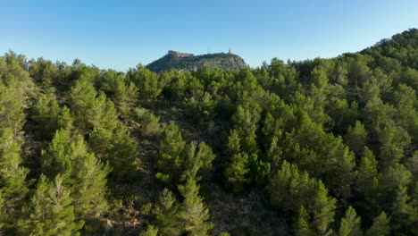 Aerial-reveal-flying-over-green-hill-showing-Sant-Salvador-on-a-mountain-top