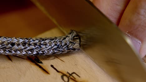 artesano hábil cortando una pulsera de color plata con un cuchillo afilado