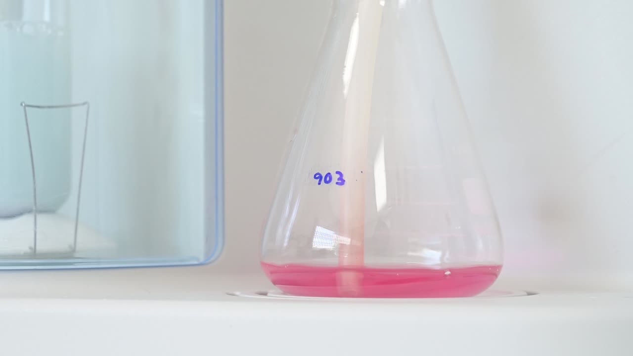 recipiente de frasco con líquido rosado que hace burbujas en un laboratorio para pruebas químicas