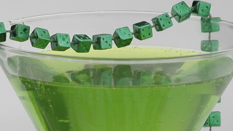 beads of green dice adorn a cocktail glass