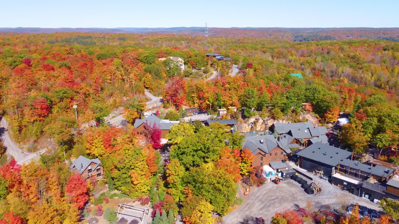 Aerial: small town and forest during the day with autumn colors in the region of Estrie, Quebec, Canada, orbit drone shot