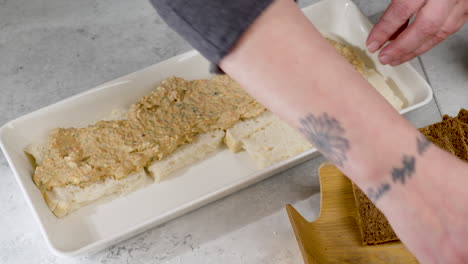 foto de un chef preparando más sándwiches en una bandeja y cepillándolos con un lavado