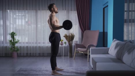 젊은 운동선수가 근육을 키우기 위해 더 열심히 일하고 있습니다. 집에서 운동하고 있습니다.