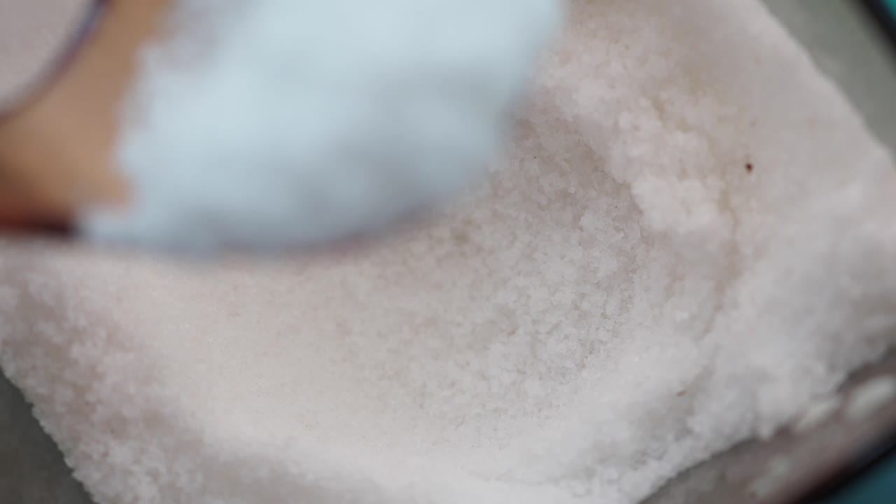 primer plano de una cuchara recogiendo sal granular blanca