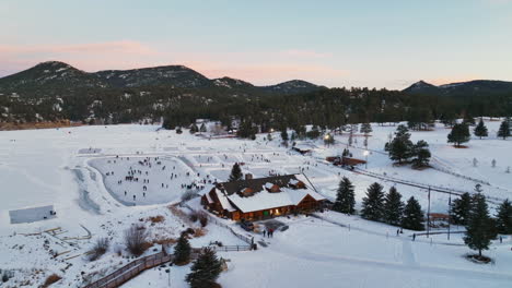 Evergreen-Lake-House-Enero-Mediados-De-Invierno-Patinaje-Sobre-Hielo,-Estanque-De-Hockey-Y-Pesca-En-Hielo-Bajo-Las-Luces-Puesta-De-Sol-Colorado-Círculo-Izquierdo-Cinemático