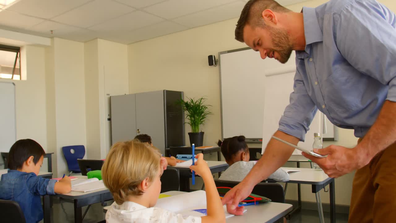 maestro de escuela caucásico adulto ayudando a un escolar en el aula de la escuela 4k