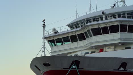 Low-angle-shot-over-cruise-ship-front-bow-in-Bergen-harbour,-seagull-stands-on-foremast