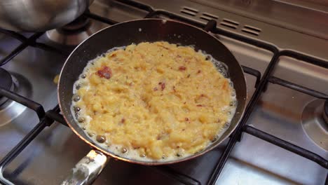primer plano de una sartén cocinando y chisporroteando la tradicional tortilla española