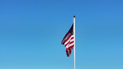 Bandera-Americana-En-Un-Poste-Ondeando-En-El-Viento-Sin-Nubes-Y-Cielo-Azul