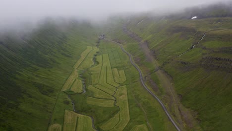 toma aérea de arriba hacia abajo de los campos agrícolas islandeses con niebla voladora en el cielo en el campo