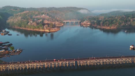 A-drone-unveiling-the-Mon-Bridge,-with-many-Mon-citizens-walking-across-it-on-a-cloudy-and-foggy-day