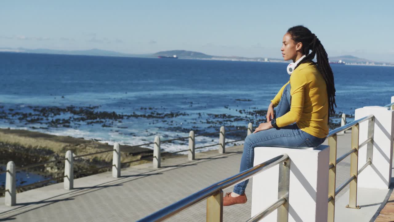아프리카계 미국인 여성 이 바 ⁇ 가 에 있는 산책로 에 앉아 있다