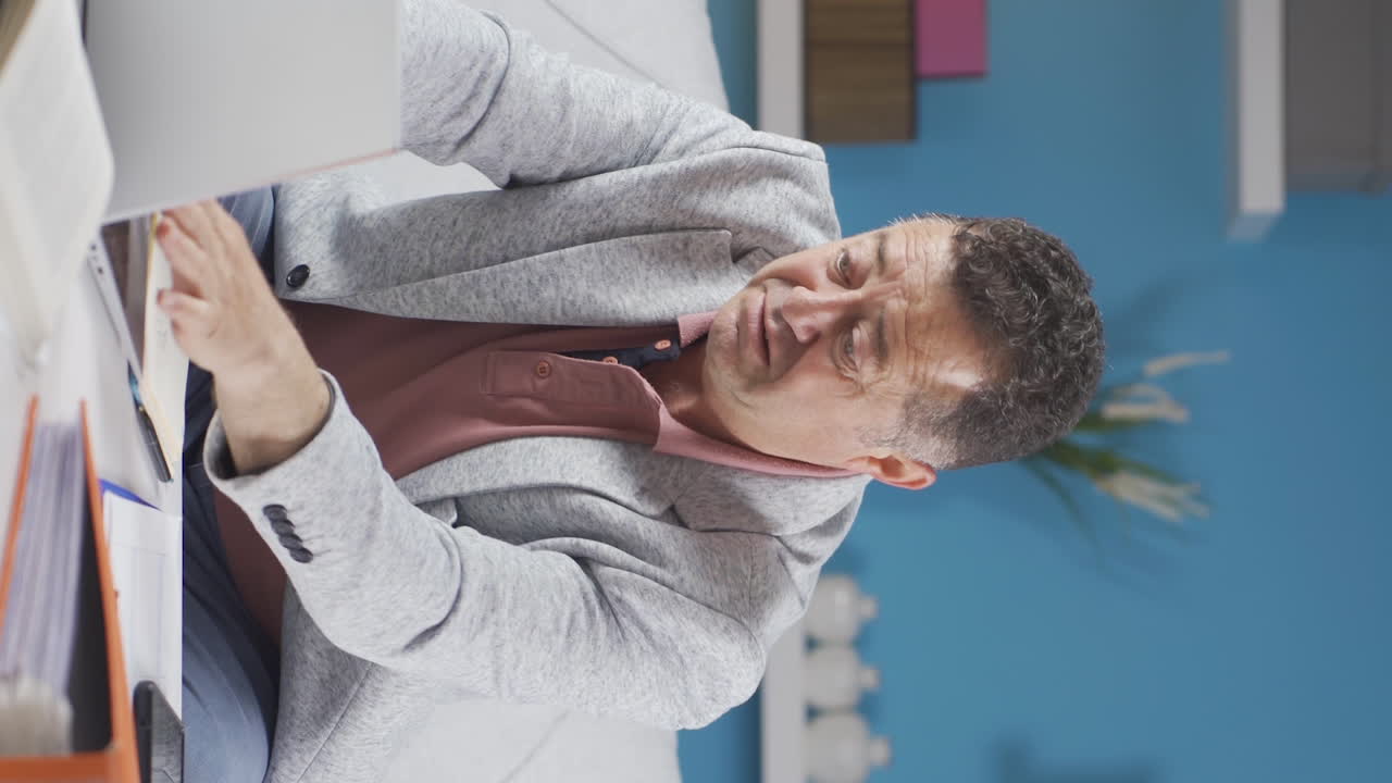 홈 오피스 직원의 수직 비디오 노인이 우울한 생각을하고 있습니다.