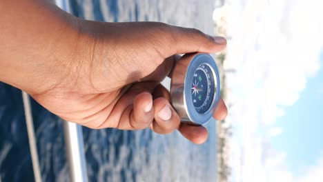 a hand holding a compass over water