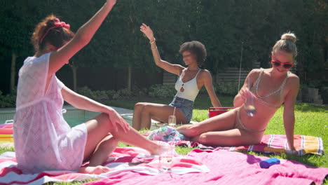 diverse female friends relaxing by pool, enjoying sunny day with drinks and laughter