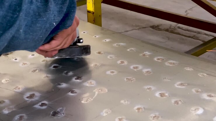 Closeup of hands grinding down metal sheet using power tool, sparks flying