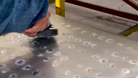 Closeup-of-hands-grinding-down-metal-sheet-using-power-tool,-sparks-flying