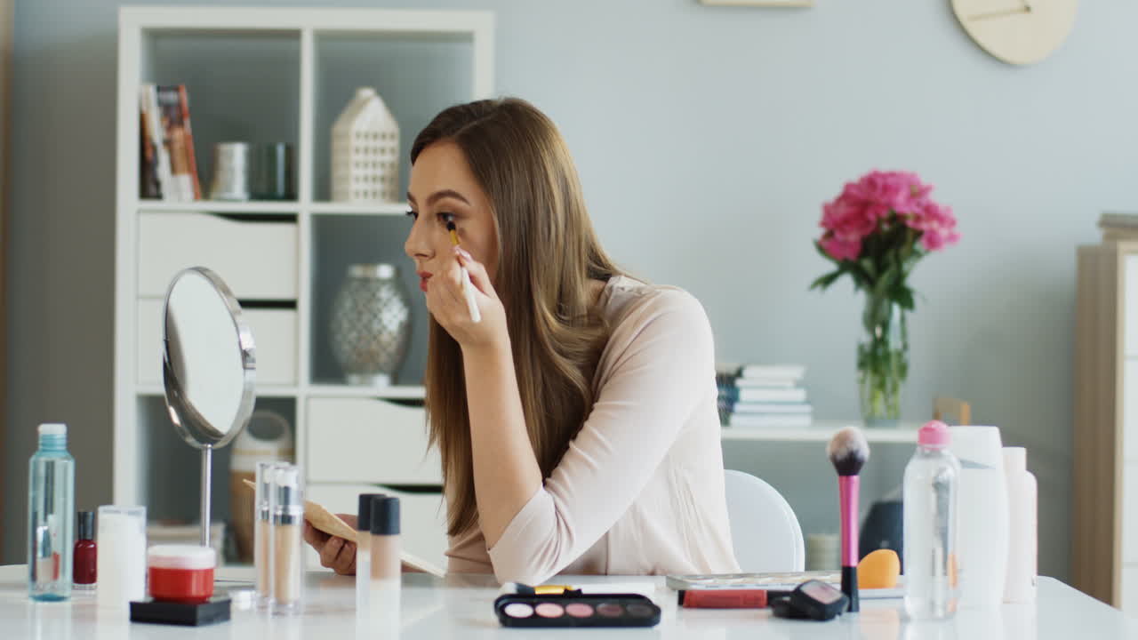 retrato de una joven sonriente aplicando sombra de ojos y mirando a la cámara