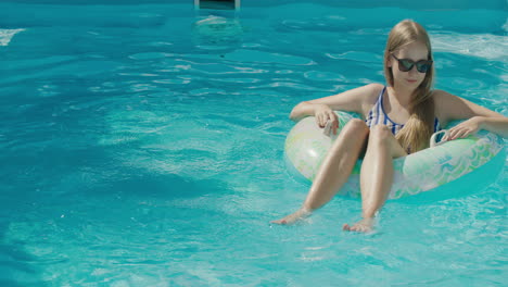 a teenage girl floats in an inflatable circle on the surface of the pool