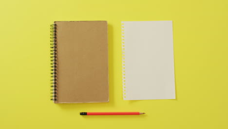 video of notebook, empty sheet with copy space and pencil on yellow background