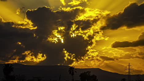 Sunset-Glow-Behind-Dark-Cloudscape-Over-Countryside-Mountains