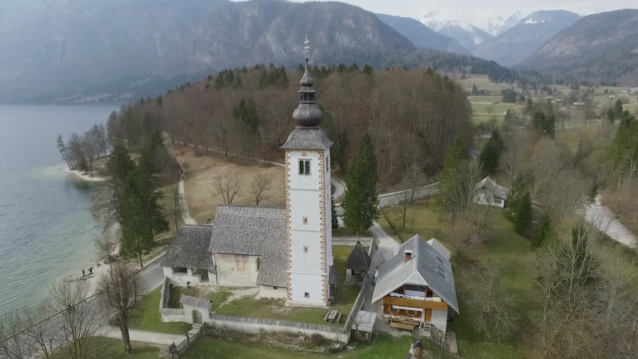 Vista da drone intorno a un ponte e una chiesa dal lago di Bohinj, Slovenia