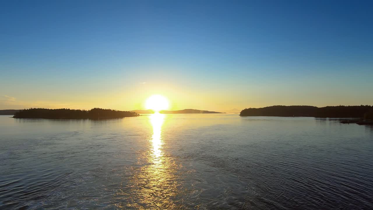 Landscape scenic view of sunset with calm sea waters, small islands, and clear blue skies during blue hour in Whistler, Canada