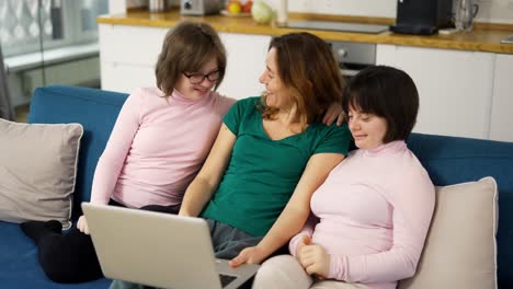 mother with two daughters down syndrome making video call using laptop