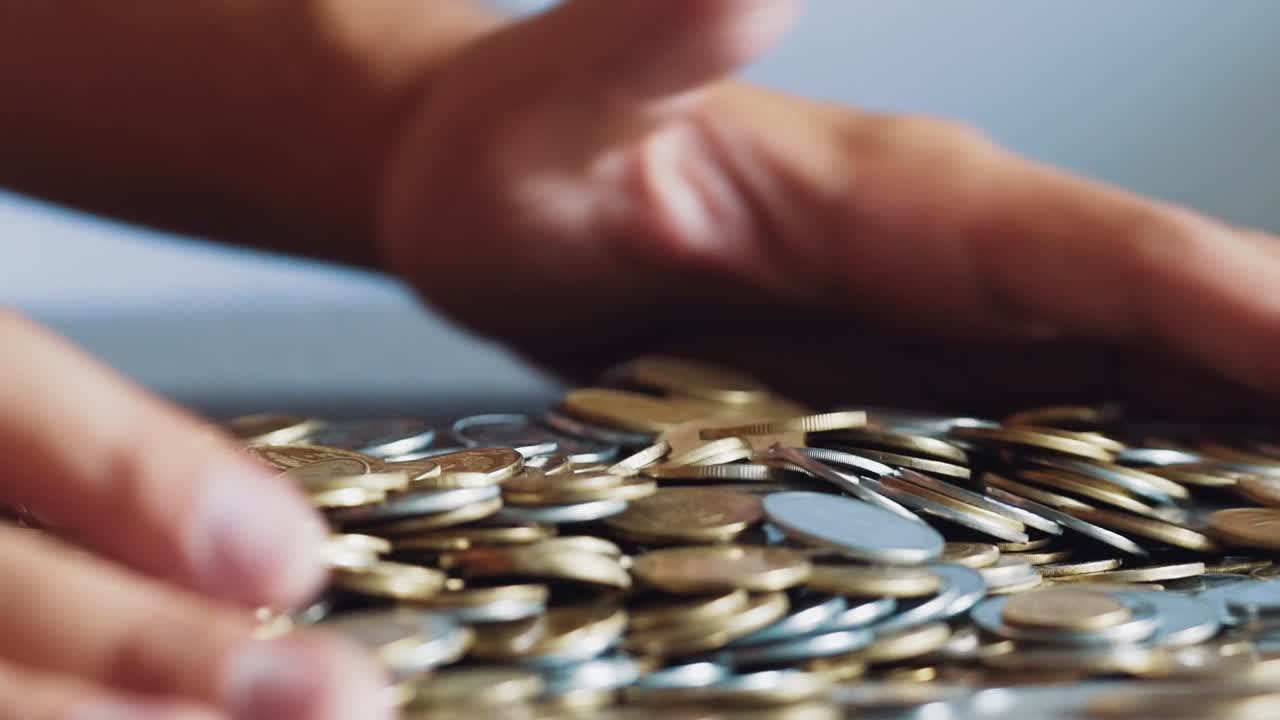Close up gold and silver coins in hand. Slow motion.