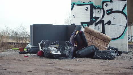 a pile of rubbish and old furniture next to a bridge pillar