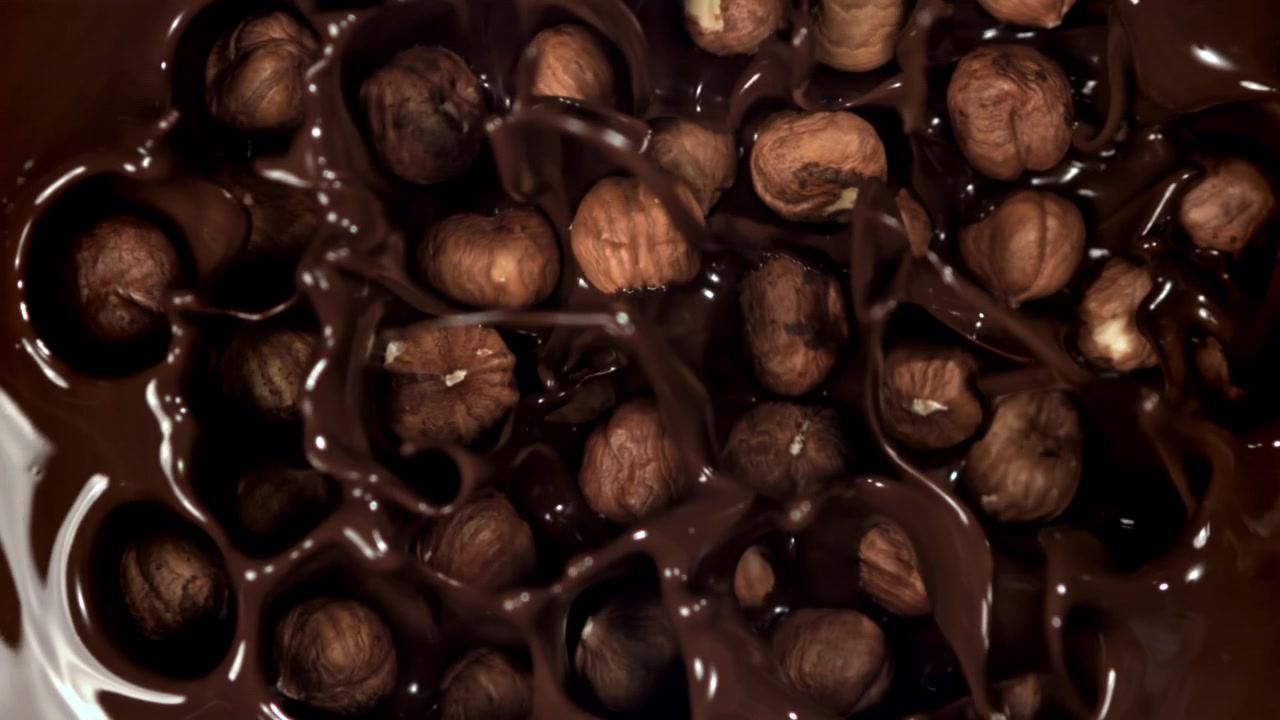 Avelãs Mergulhando em Chocolate Derretido Intenso em Câmera Lenta