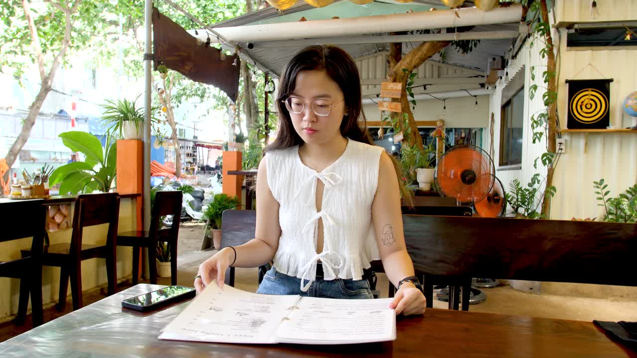 Asian Girl Checking Food Menu At Vietnamese Restaurant. medium shot