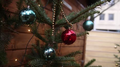 red and green christmas ornaments hanging on a tree in front of wooden chalet in heidelberg, germany at a festive christmas market in europe