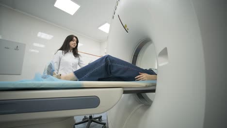 female patient is undergoing ct or mri scan under supervision of a radiologist in modern medical clinic. patient lying on a ct or mri scan bed, moving inside the machine.