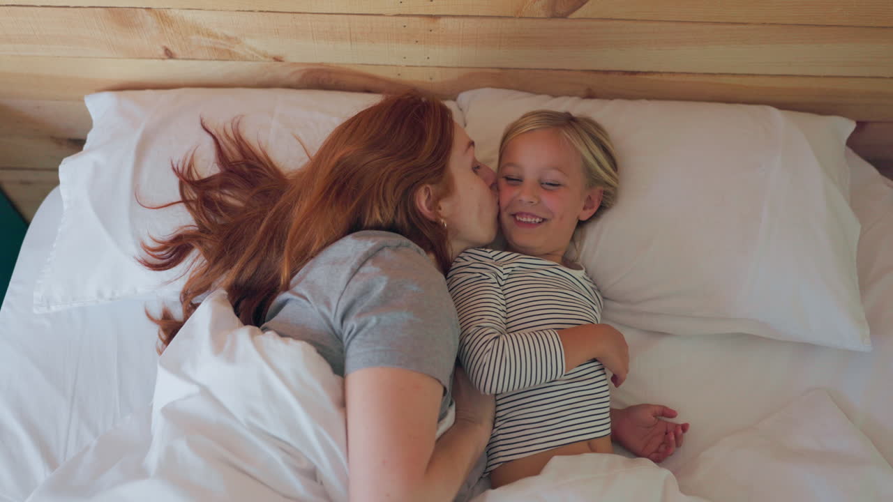 Letto, risveglio e una mamma che bacia la figlia
