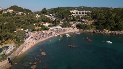 Drone-ascends-above-water-to-showcase-boat-leaving-dock-as-tourists-play-and-relax-in-Corfu-Greece